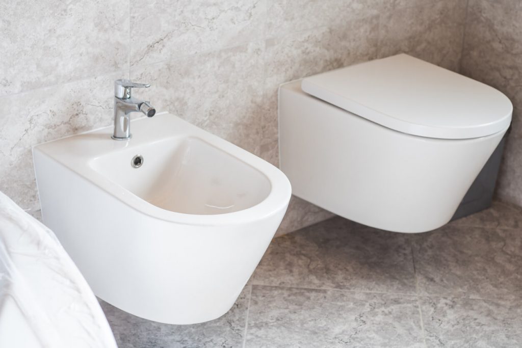 Weiße Toilette und Bidet auf Keramikfliesen
