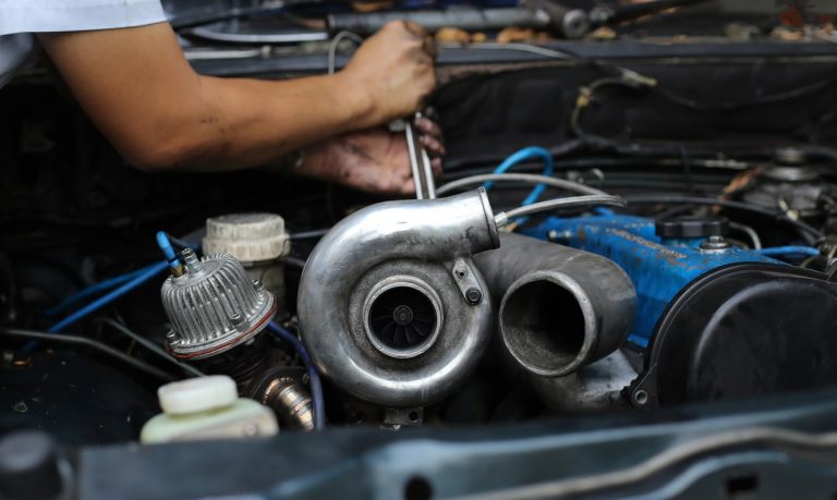 Automechaniker schraubt an einem alten defekten Turbolader eines Autos