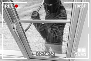Einbrecher mit Sturmmaske und Brecheisen versucht ein Fenster aufzuhebeln