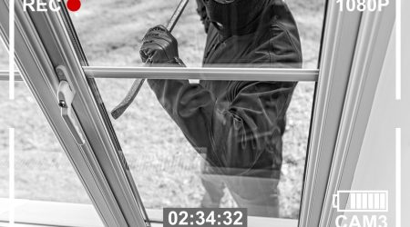 Einbrecher mit Sturmmaske und Brecheisen versucht ein Fenster aufzuhebeln