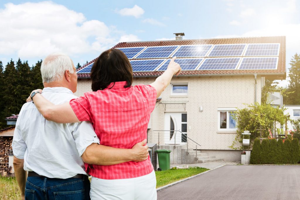 Paar zeigt auf ein Haus mit Photovoltaik.