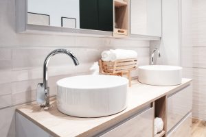 Zwei weiße, moderne, luxuriöse Waschbecken auf einem hellen Waschschrank