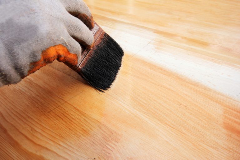 Bodenleger versiegelt Laminatboden mit Pinsel