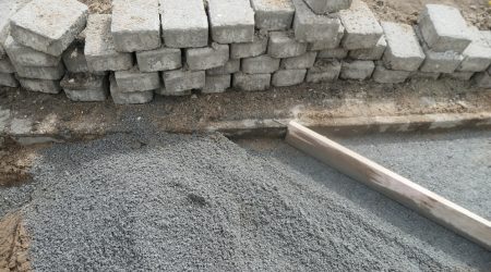 Pflastersteine mit Split als Untergrund aufgeschlichtet an einer zu pflasternden Fläche