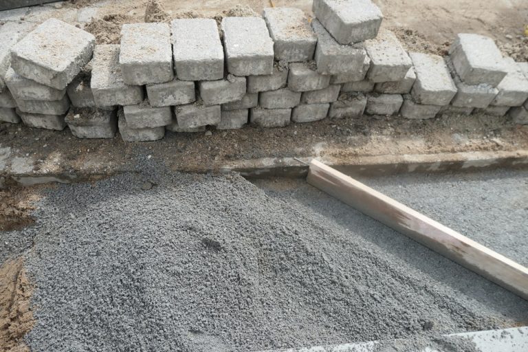 Pflastersteine mit Split als Untergrund aufgeschlichtet an einer zu pflasternden Fläche