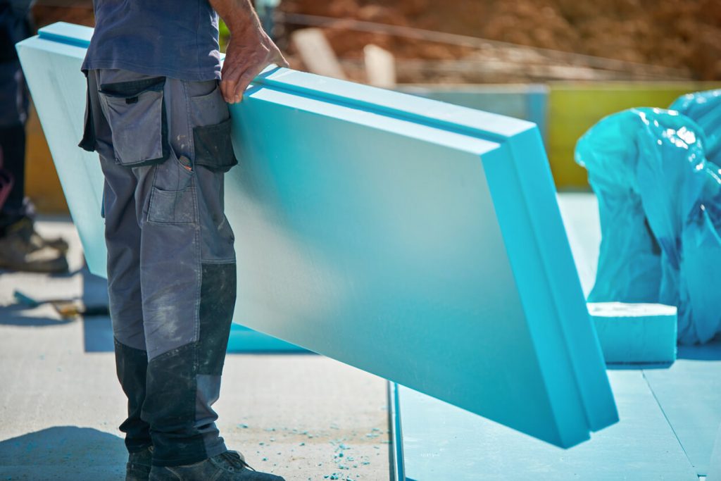 Arbeiter mit Platten zur Wärmedämmung auf einem Umkehrdach
