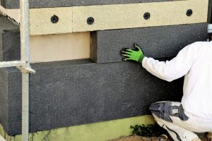 Maler bringt Dämmplatten zur Außendämmung an einer Fassade an