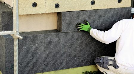 Maler bringt Dämmplatten zur Außendämmung an einer Fassade an