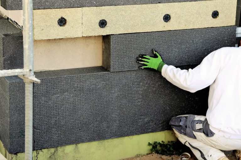 Maler bringt Dämmplatten zur Außendämmung an einer Fassade an