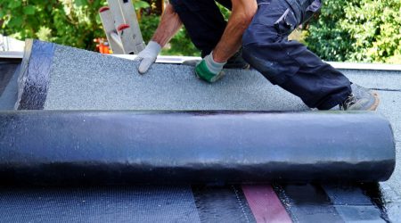 Dachdecker auf einem Flachdach, der eine Flachdachdämmung anbringt