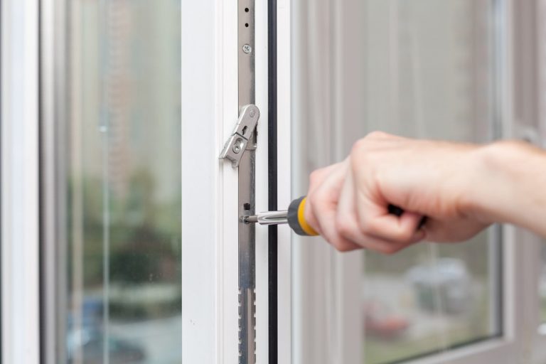 Handwerker montiert einen Fensterbeschlag an einem weißen Kunststofffenster
