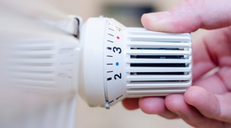 Hand einer einem Heizungsthermostat