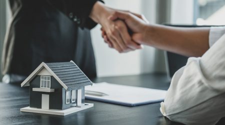 Immobilienmakler und Käufer geben sich nach der Unterzeichnung eines Immobilienkaufvertrags den Handschlag
