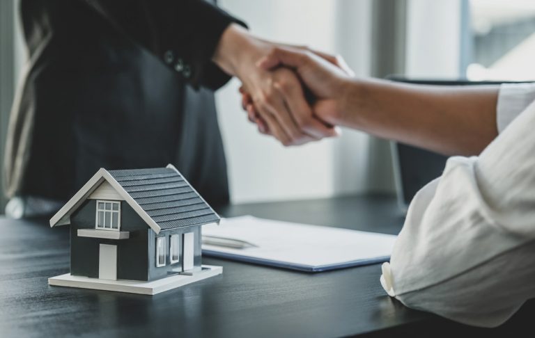 Immobilienmakler und Käufer geben sich nach der Unterzeichnung eines Immobilienkaufvertrags den Handschlag