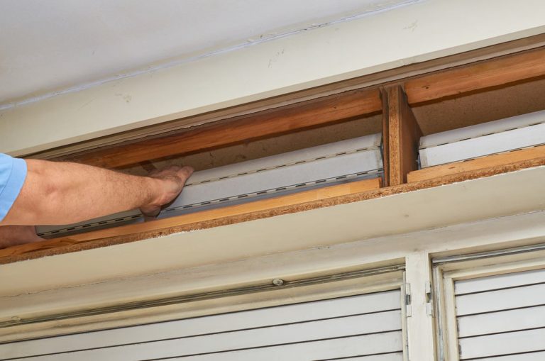 Handwerker fixiert Jalousie in einem Rolladenkasten für die Dämmung