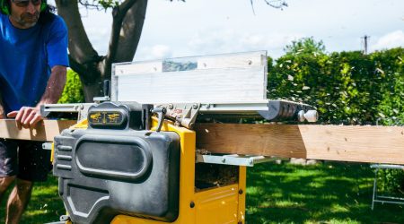 Dachdecker sägt Dachsparren in einem Garten zurecht