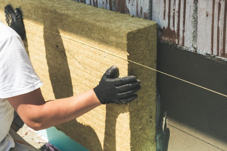 Handwerker bringt Dämmplatte aus Steinwolle an einer Hauswand an
