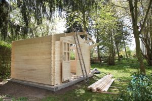 Ein Gartenhaus aus hellem Holz im Aufbau mit angelehnter Leiter
