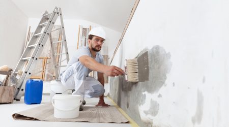 Maler bringt Grundierung gegen Schimmel an einer Wand mit einem Pinsel an
