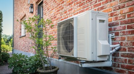 Wärmepumpe hängt außen an einer Klinkerfassade