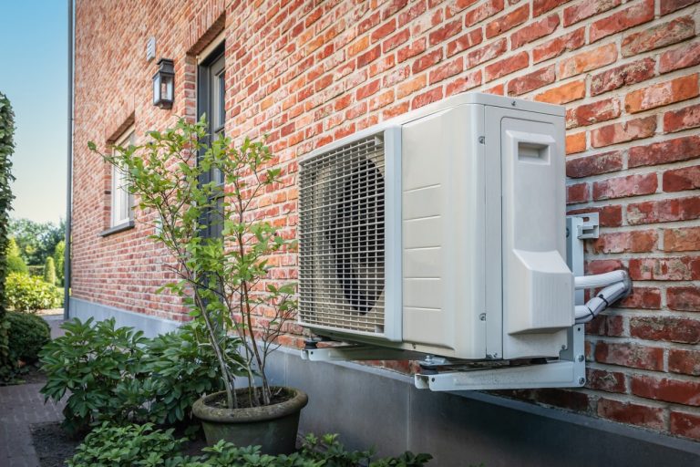 Wärmepumpe hängt außen an einer Klinkerfassade