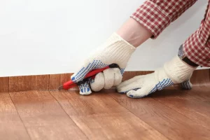 Bodenleger schneidet beim Verlegen von Linoleum die überstehenden Kanten mit einem Cuttermesser