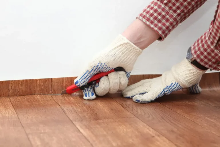 Bodenleger schneidet beim Verlegen von Linoleum die überstehenden Kanten mit einem Cuttermesser