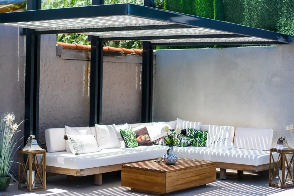 Überdachte Sitzgruppe mit weißen Polstern auf einer Terrasse im Sommer