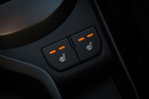 Nahaufnahme einer Konsole im Innenraum eines Autos mit zwei Knöpfen zum Aktivieren der Sitzheizung