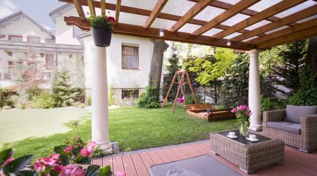 Terrassenüberdachung aus Holz auf zwei Steinsäulen in einem Garten
