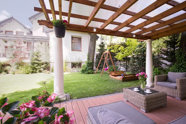 Terrassenüberdachung aus Holz auf zwei Steinsäulen in einem Garten