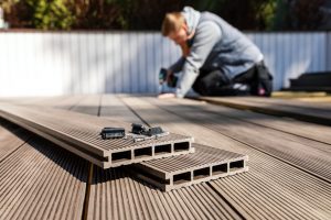 Handwerker verlegt WPC Dielen beim Terrassenbau