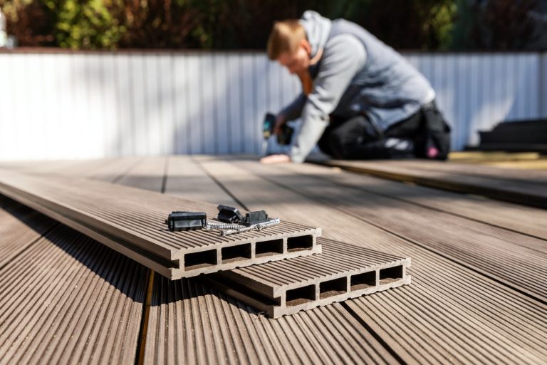 Handwerker verlegt WPC Dielen beim Terrassenbau