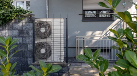 Wärmepumpe als alternatives Heizsystem vor einem Wohnhaus