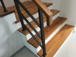 Holztreppe mit schwarzem Stahlgeländer und modernem Handlauf aus Holz