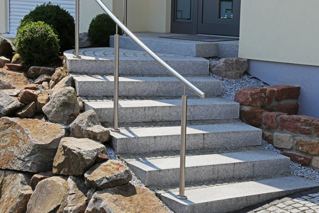 Steintreppe im Außenbereich eines Gartens mit einem Handlauf aus Edelstahl