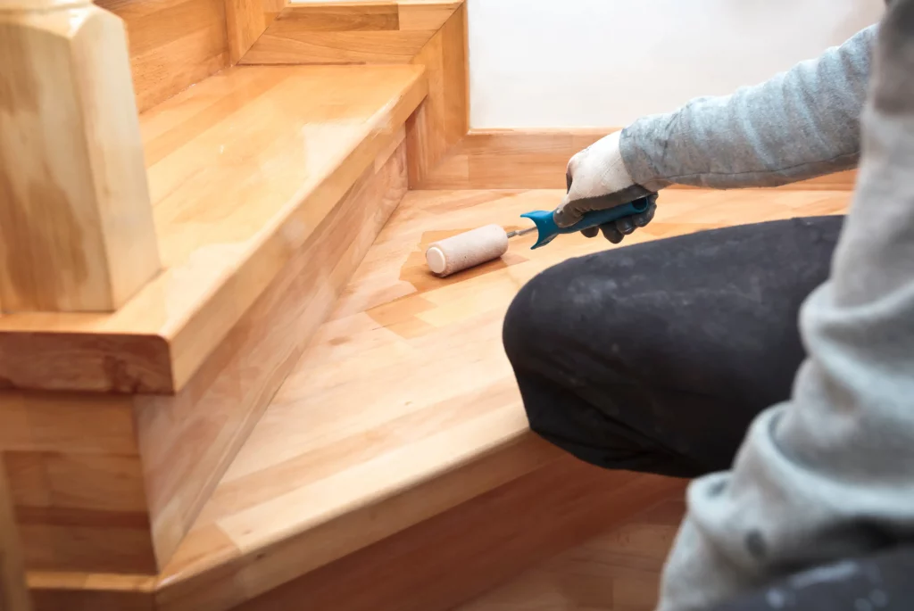 Handwerker lackiert eine frisch renovierte Holztreppe