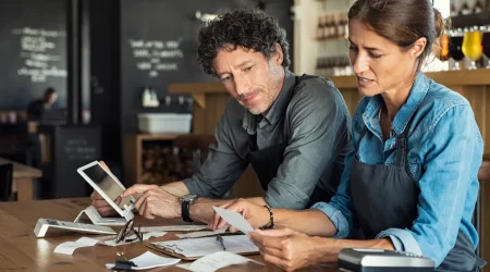 Zwei Kleinunternehmer sitzen in ihrem kleinen Café über einer Abrechnung