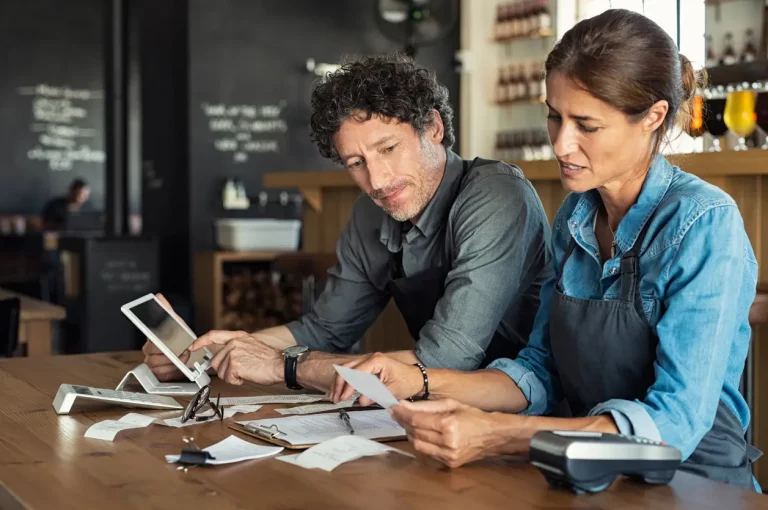Zwei Kleinunternehmer sitzen in ihrem kleinen Café über einer Abrechnung