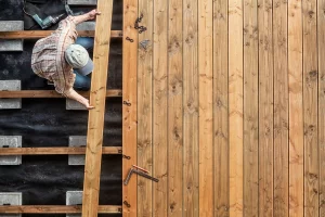 Gartenbauer verlegt Terrassendielen aus Holz auf eine Unterkonstruktion in einem Garten