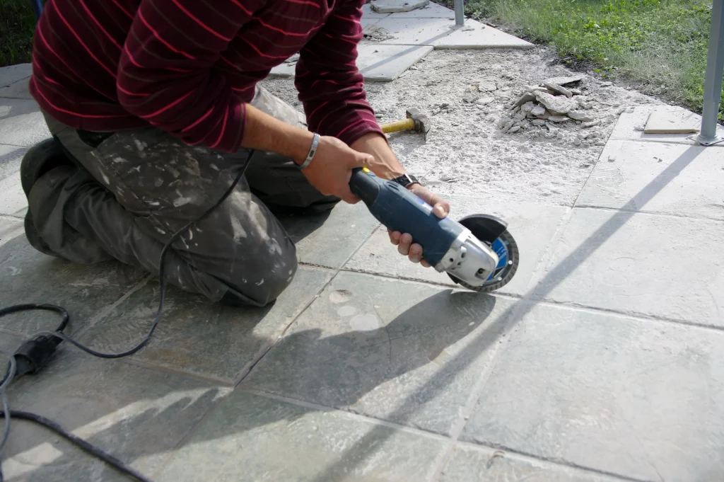 Handwerker entfernt Terrassenplatten bei einer Terrassensanierung