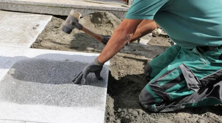 Gartenbauer verlegt ein Plattenfundament für ein Gartenhaus