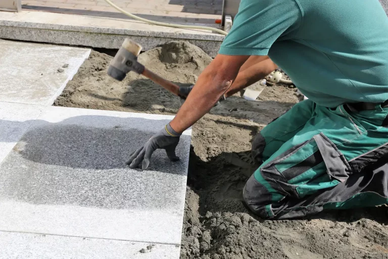 Gartenbauer verlegt ein Plattenfundament für ein Gartenhaus