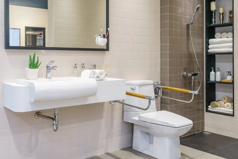 Seniorengerechtes Badezimmer mit Toilette mit Griffen und angepasstem Waschbecken