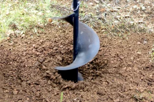 Kleiner Bohrer dreht sich in den Boden um einen Brunnen zu bohren und wirbelt dabei Erde auf