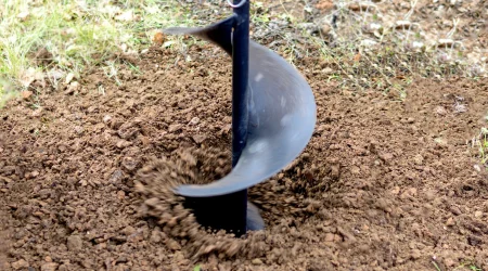 Kleiner Bohrer dreht sich in den Boden um einen Brunnen zu bohren und wirbelt dabei Erde auf