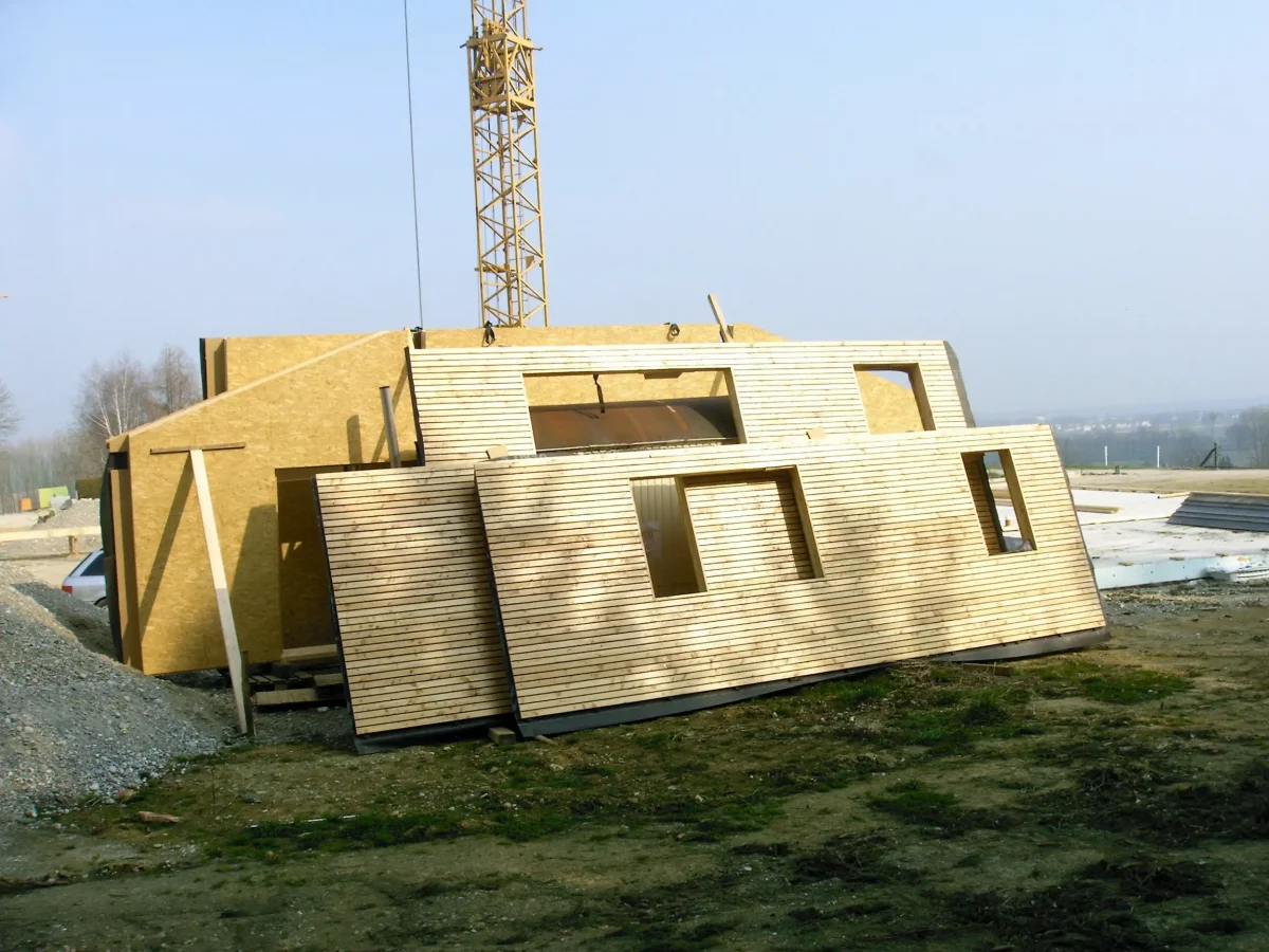 Fertighaus Bauteile aus Holz angelehnt an einen Baukran