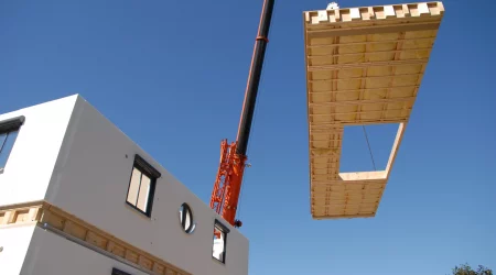 Kran hebt Bauteil für Fertighaus