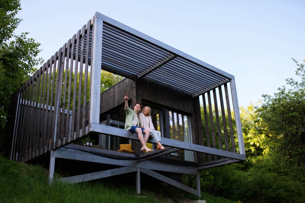 Junges Paar sitzt auf der Terrasse eines Tinyhouses am Hang