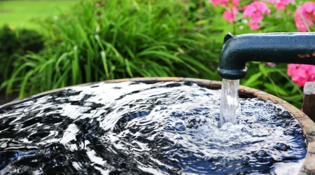 Nahaufnahme eines Grundwasserbrunnens. Wasser fliest aus dem Hahn des Brunnens in ein Auffangbecken